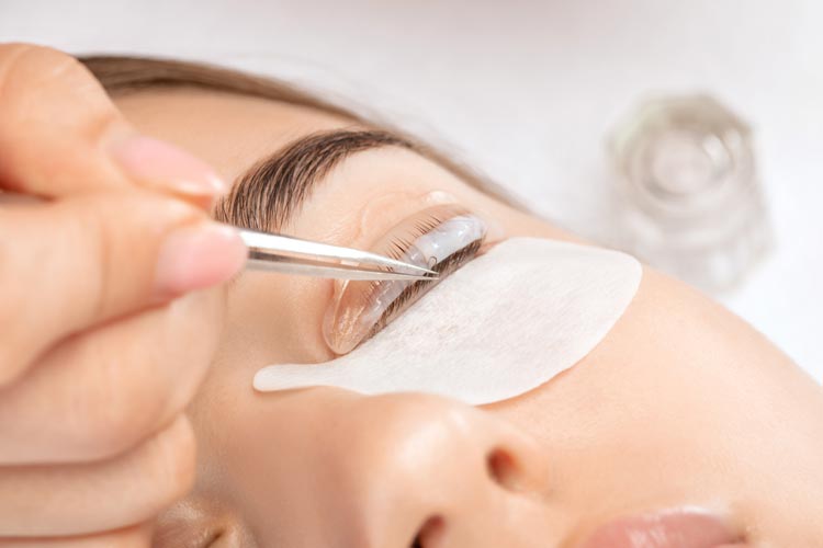 Fransstylist håller i en pincett och genomför en lashlift behandling på kunden