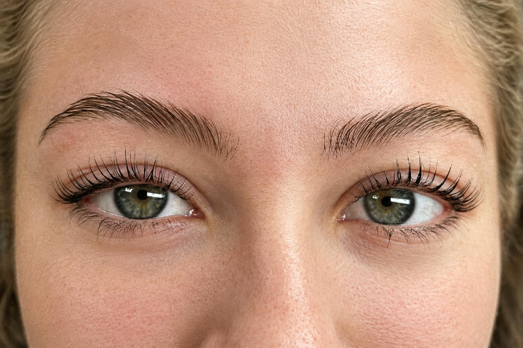 Närbild på kundens ögon efter lashlift och browlift med vackert lyfta fransar och fylliga, välformade och definierade ögonbryn